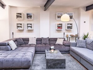 Un salon moderne avec un canapé d’angle, une table basse et des étagères murales pour les chaussures.