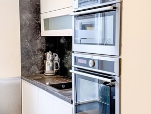 A kitchen with a built-in oven and a coffee maker on the counter.