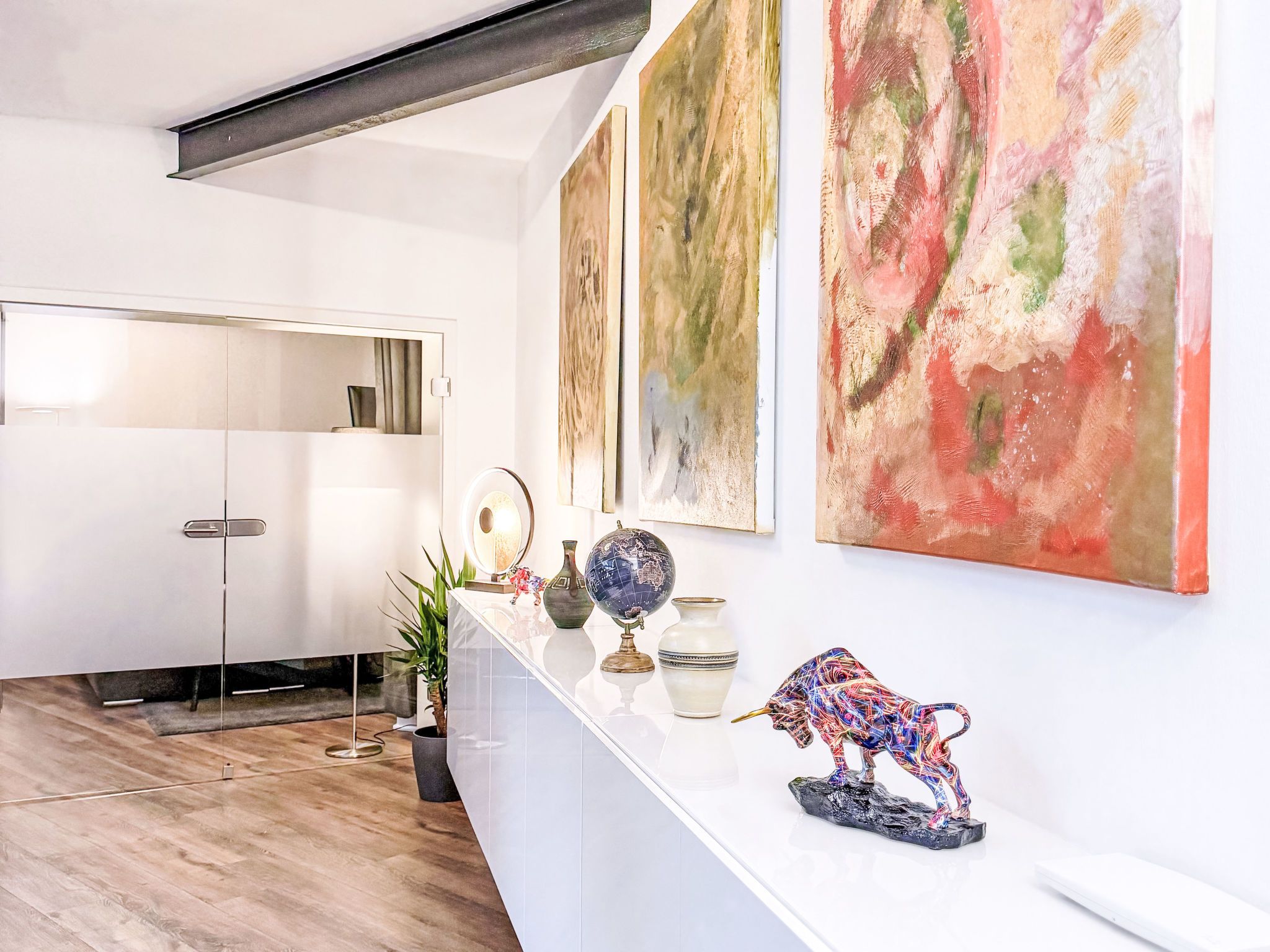 Ein modernes Interieur mit einem weißen Empfangstresen, abstrakten Gemälden und einem Globus.