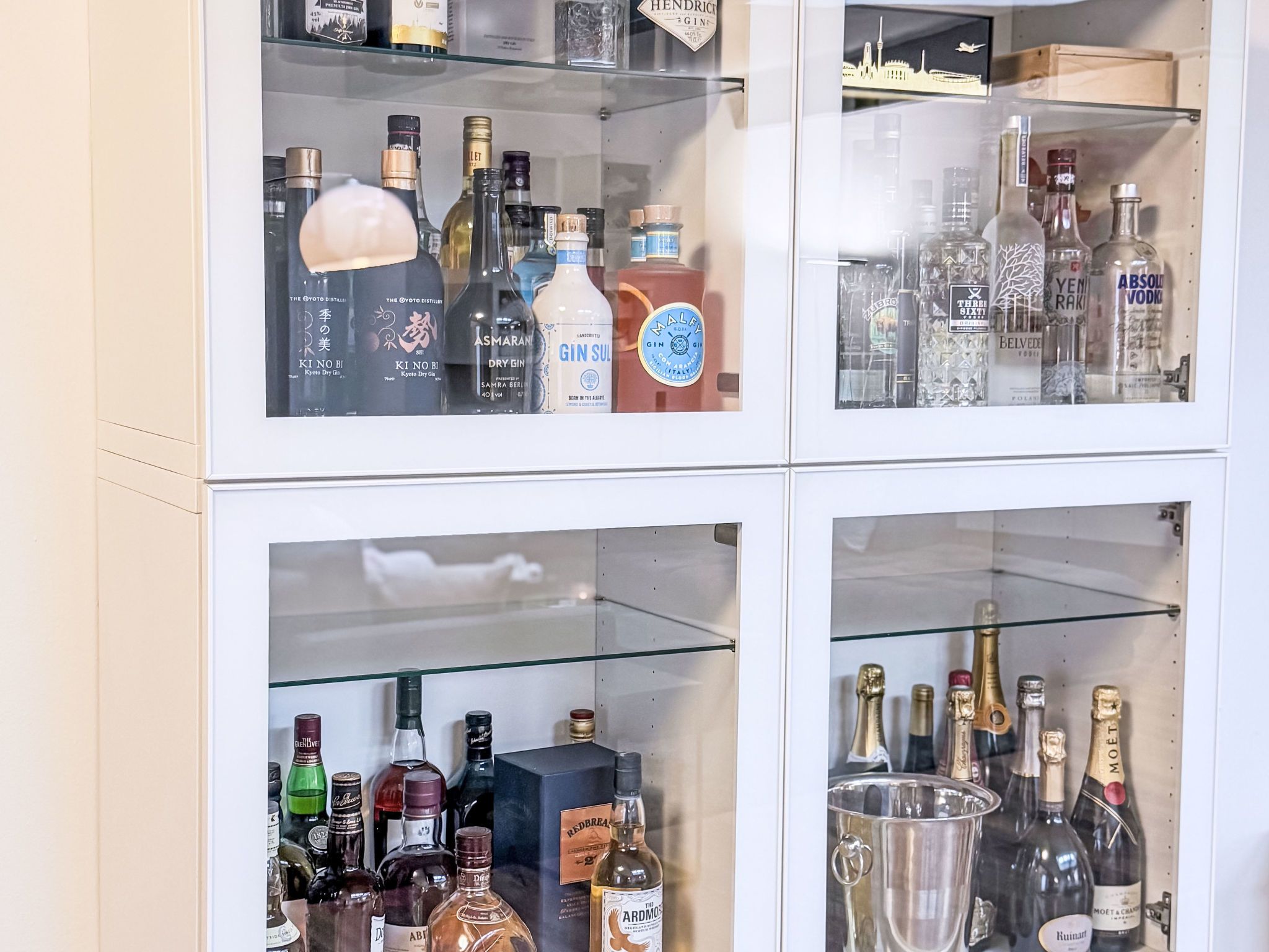 Eine Getränkeschrank mit verschiedenen Flaschen Gin, Wodka und anderen Spirituosen.
