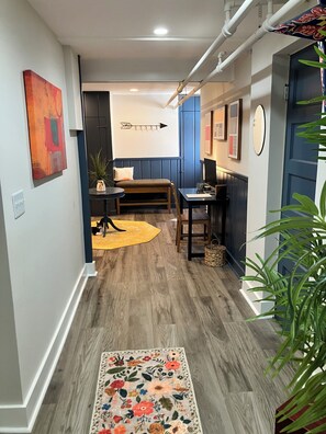 Ein Korridor mit Holzboden, einer Bank, einem Tisch und einem Stuhl.