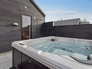Ein Whirlpool in einer Außenanlage mit einer Holzverkleidung und einem Metalldach.