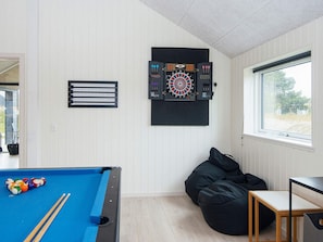 A room with a pool table, a dartboard, a bean bag chair, and a window. - Luxury Retreat With Pool (Rømø)