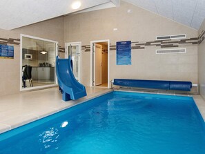 Ein Hallenbad mit einer blauen Rutsche, einer Küchenzeile und einer Tür zu einem weiteren Raum.