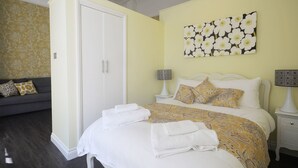 Een slaapkamer met een bed, twee nachtkastjes, een bank en een deur.