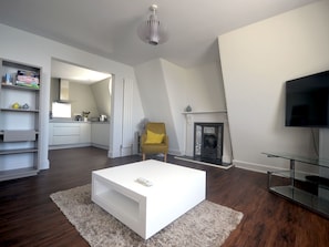 A modern living room with a white sofa, a yellow armchair, a fireplace, and a TV. - Helle, erst kürzlich vollständig renovierte (2016) Ferienwohnungen in einem den by Interhome (Plymouth)