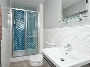 Ein modernes Badezimmer mit Duschkabine aus Glas, einer weißen Toilette und einem großen Waschbecken.