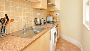 A kitchen with a sink, stove, and washing machine. - in Torquay by Interhome (Torquay)