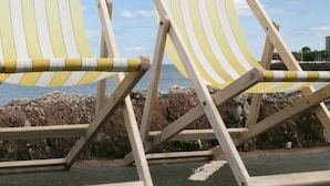 Two striped beach chairs with a rocky shoreline and a clear sky in the background. - in Torquay by Interhome (Torquay)