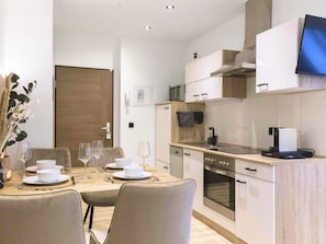 A modern kitchen with a built-in oven, microwave, and a flat-screen TV mounted above the counter. - Apartment, Küche, Parkplatz, digitaler Check-in by Interhome (Hof)