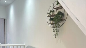 Un soggiorno moderno con due divani grigi, un piccolo tavolino nero con una lampada bianca e una mensola a muro per piante.
