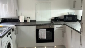 Una cucina compatta con lavatrice, forno a microonde, tostapane e piccolo forno.