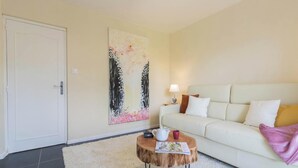 A living room with a white sofa, a round coffee table, a painting on the wall, and a door. - L'Atelier de la Mandille (SAINT ELIX LE CHATEAU)