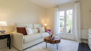 Ein Wohnzimmer mit einer Couch, einem Couchtisch, einer Lampe und einem Fenster mit Vorhängen.