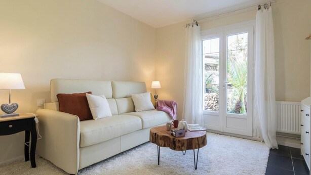 A living room with a sofa, a coffee table, a lamp, and a window with curtains. - L'Atelier de la Mandille (SAINT ELIX LE CHATEAU)