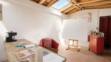 A room with a wooden ceiling, a skylight, a red chair, a whiteboard, and a red cabinet with art supplies.