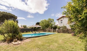 Un jardin avec une piscine, un mur en pierre et une maison.