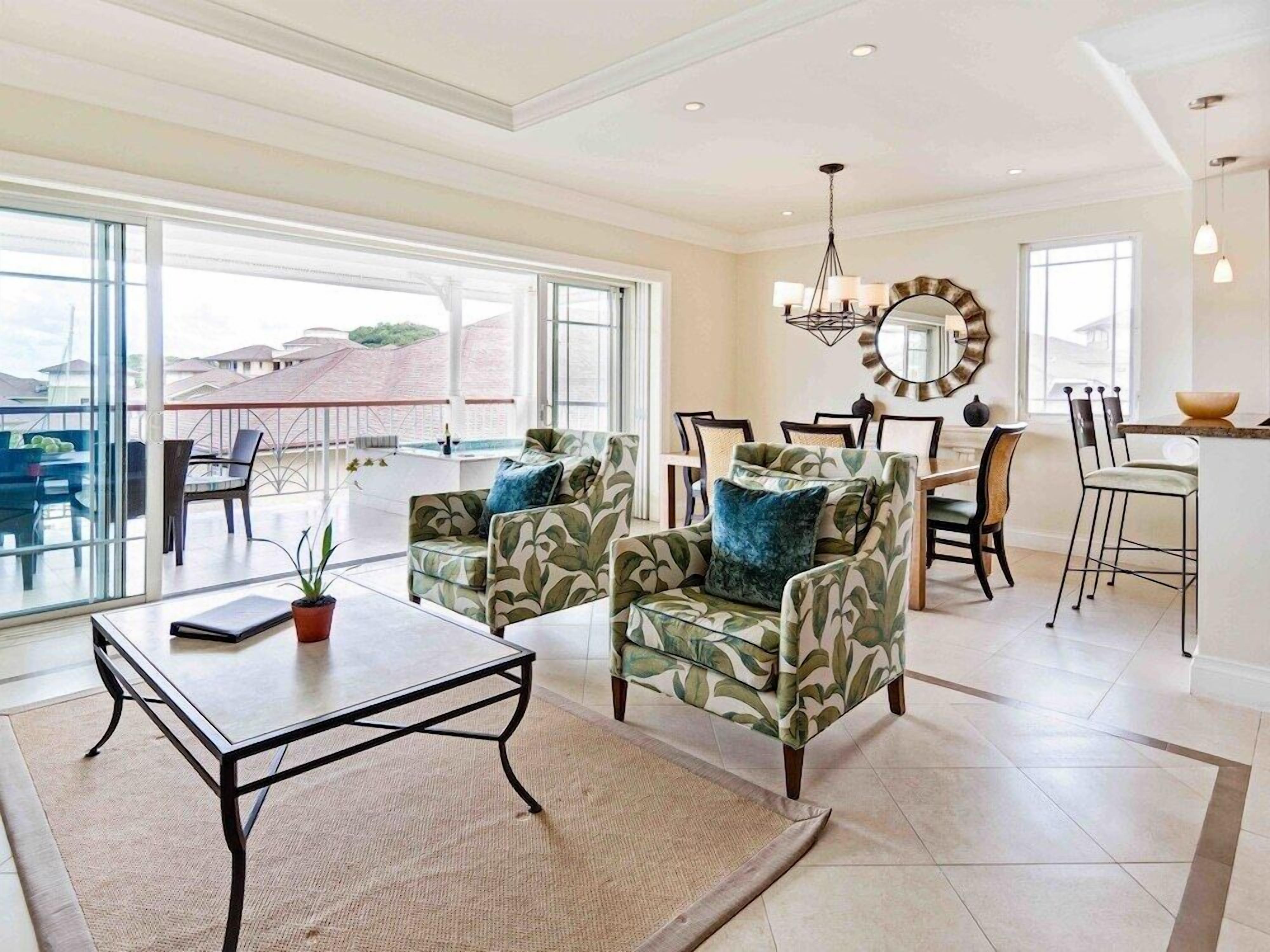 A spacious living area with a balcony, a dining set, and a kitchen area.