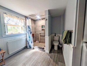 Un baño con ducha, inodoro y ventana.
