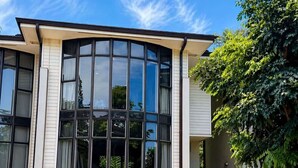A modern two-story house with large windows, a garage, and a staircase leading to the entrance. - Walk to beach, 3BR Beach Escape, Amazing Value (Lahaina)