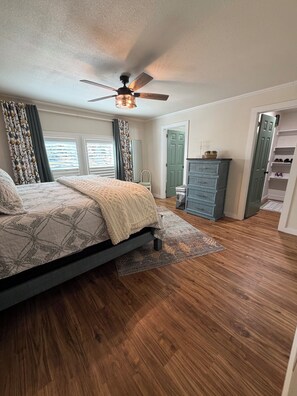 A bedroom with a bed, a ceiling fan, a dresser, and a walk-in closet. - Your lakefront retreat with private boat slip, firepit, game room & wildlife ❤️ (Canadian)