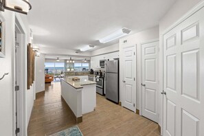 A modern kitchen with a central island, stainless steel appliances, and a view to the outside. - New! Gulf-Front Luxury | 2 King Suites | Pool | Beach Service | Free Activities! | Summerlin 104 (Fort Walton Beach)