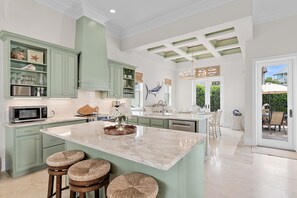 A spacious kitchen with a large island, green cabinetry, and a view to the outside. - Blue Mountain Bella | Pool + Golf Cart + Steps to Beach (Santa Rosa Beach)