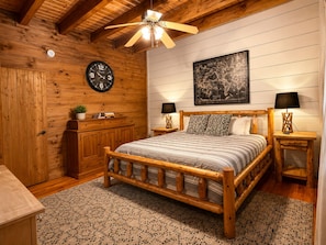 Une chambre à coucher en bois, avec un lit, une horloge, une carte et un ventilateur de plafond.
