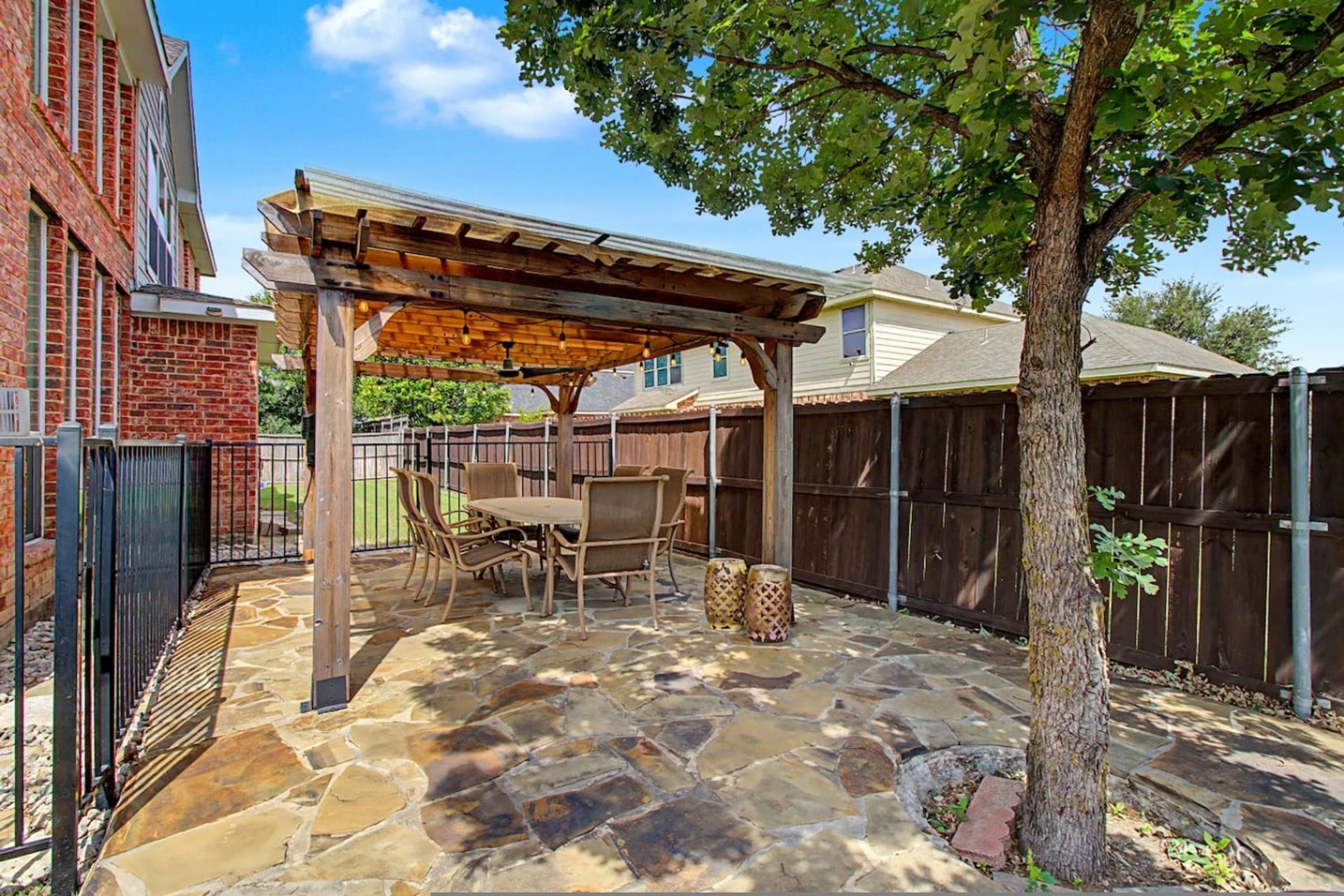 A patio with stone flooring, a pergola, and outdoor furniture.