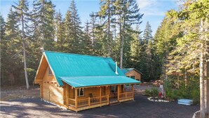 A log cabin with a green roof, surrounded by a forest. - Modern Log Cabin w/ Private Fire Pit – Mins to Lake Kachess & Snoqualmie Pass (Easton)