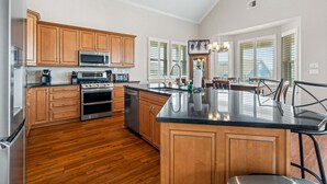 Una cocina con armarios de madera, electrodomésticos de acero inoxidable, una isla grande y un comedor con vistas.
