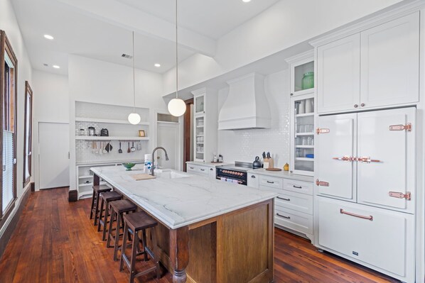 Una cocina moderna con una isla grande, armarios blancos y piso de madera.