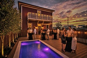 Un área junto a la piscina con terraza de madera, una piscina y un edificio con balcón.