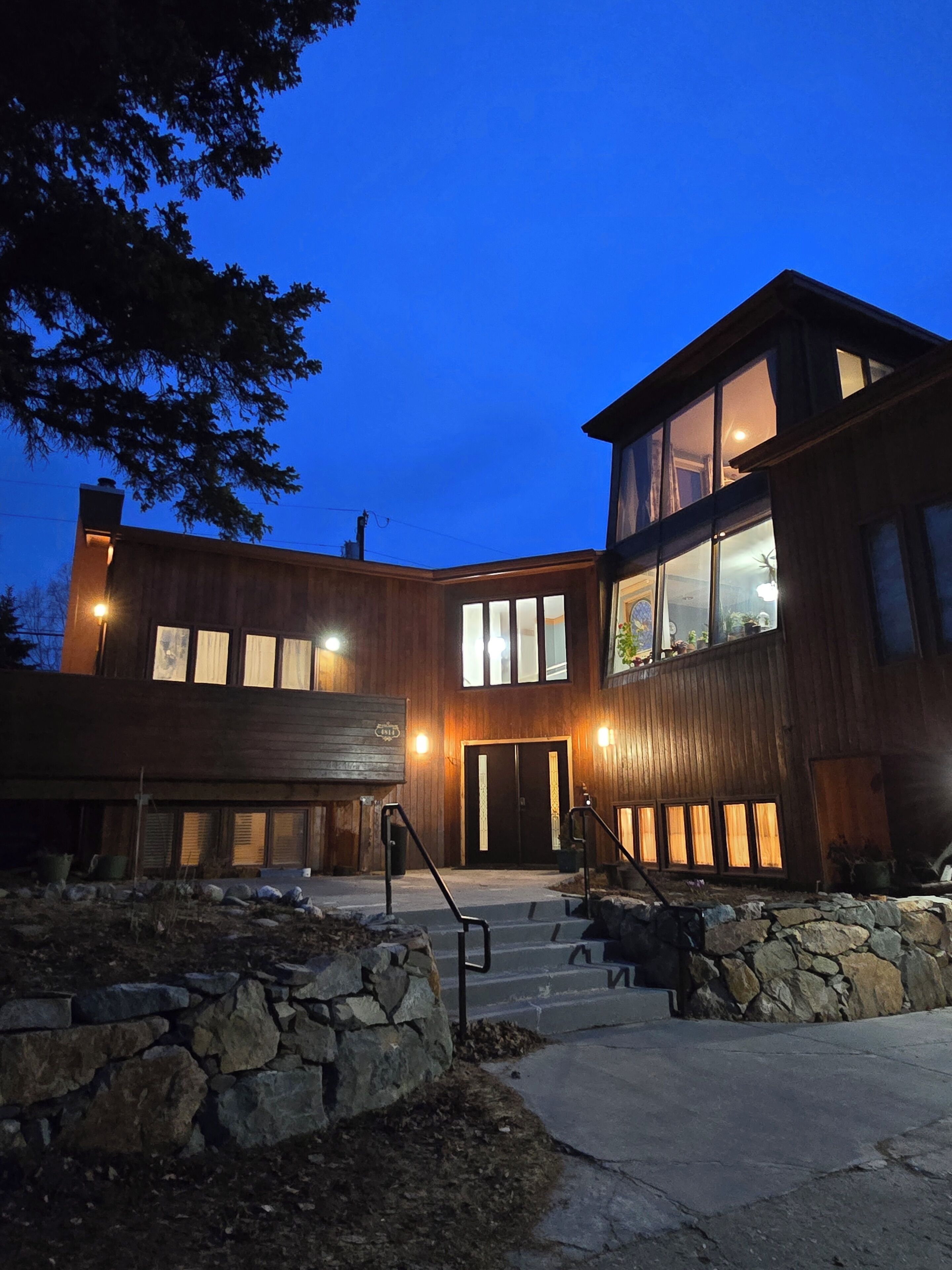 A modern building with a stone foundation, a wooden facade, and a large entrance with steps.