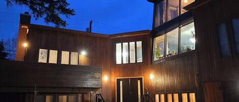 A modern building with a stone foundation, a wooden facade, and a large entrance with steps.