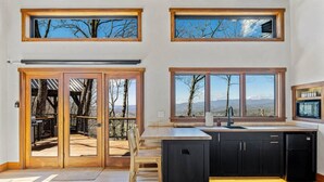 Una cocina moderna con ventanas amplias, un comedor con vistas y una puerta corrediza de vidrio que da a una terraza exterior.