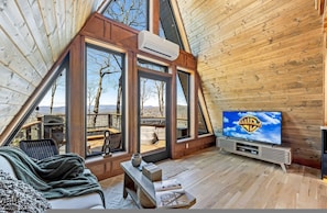 A cozy room with a large window, a television, and a wooden ceiling. - A-frame Retreat Hot Tub Mtn Views Spa Bath (Penrose)