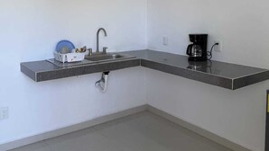 A modern kitchen with a built-in sink, a coffee maker, and a ceiling fan.