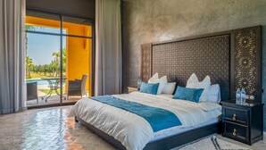 Un dormitorio con una cama grande, una mesita de noche, vista a una piscina y una zona de patio.