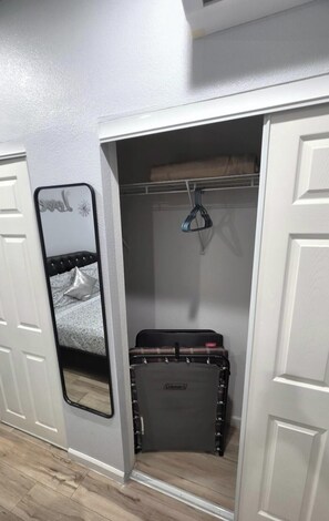 A walk-in closet with a mirrored closet door, a hanging rack, and a suitcase. - Ithaca Oasis (Las Vegas)