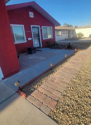 A red building with a paved driveway, a small garden, and a gravel path. - Ithaca Oasis (Las Vegas)