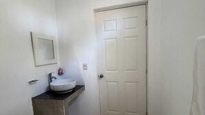 Een kleine badkamer met toilet, wastafel en een deur.