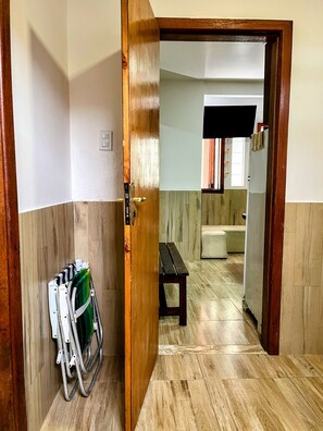 A hallway with a wooden door, a metal folding chair, a bench, and a bathroom in the background. - House on Second Beach | 2 Bedrooms | 2 Bathrooms | Air Conditioning (Morro de São Paulo)