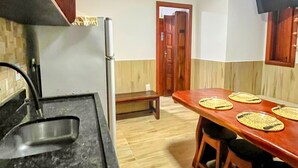Eine Küche mit schwarzem Arbeitsplatz, einem Holzespeisetisch mit Platzsets und einer Holztür im Hintergrund.
