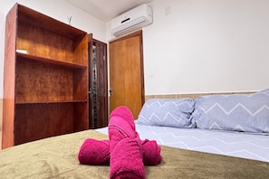 Una habitación con cama, armario de madera y aire acondicionado.