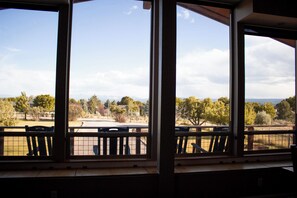 Ein Zimmer mit großen Fenstern und Blick auf einen Park sowie entfernte Berge.
