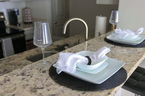 A kitchen counter with a glass of water, a white napkin, and a plate with a napkin holder.