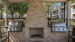 An outdoor patio with two gas grills, a brick chimney, and a ceiling fan. - 3 mins from Arsenal/Bridge Street (Huntsville)