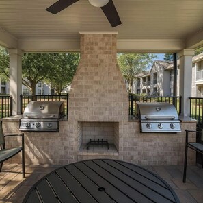 An outdoor patio with two gas grills, a brick chimney, and a ceiling fan. - 3 mins from Arsenal/Bridge Street (Huntsville)