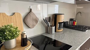 A modern kitchen with a black induction cooktop, a coffee maker, and a knife holder. - Florida Metro Premium Studio + Parking + View (La Florida)